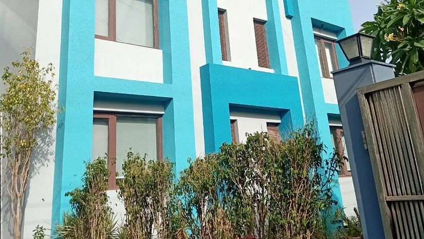An exterior view of a multi-level building with rectangular windows, a sectioned facade, and a fence with greenery at the base - Asian Suites IFFCO Chowk Metro Station, Gurgaon. 