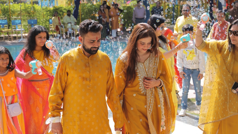 Couple walking during a vibrant haldi ceremony celebration at Umaid Palace.