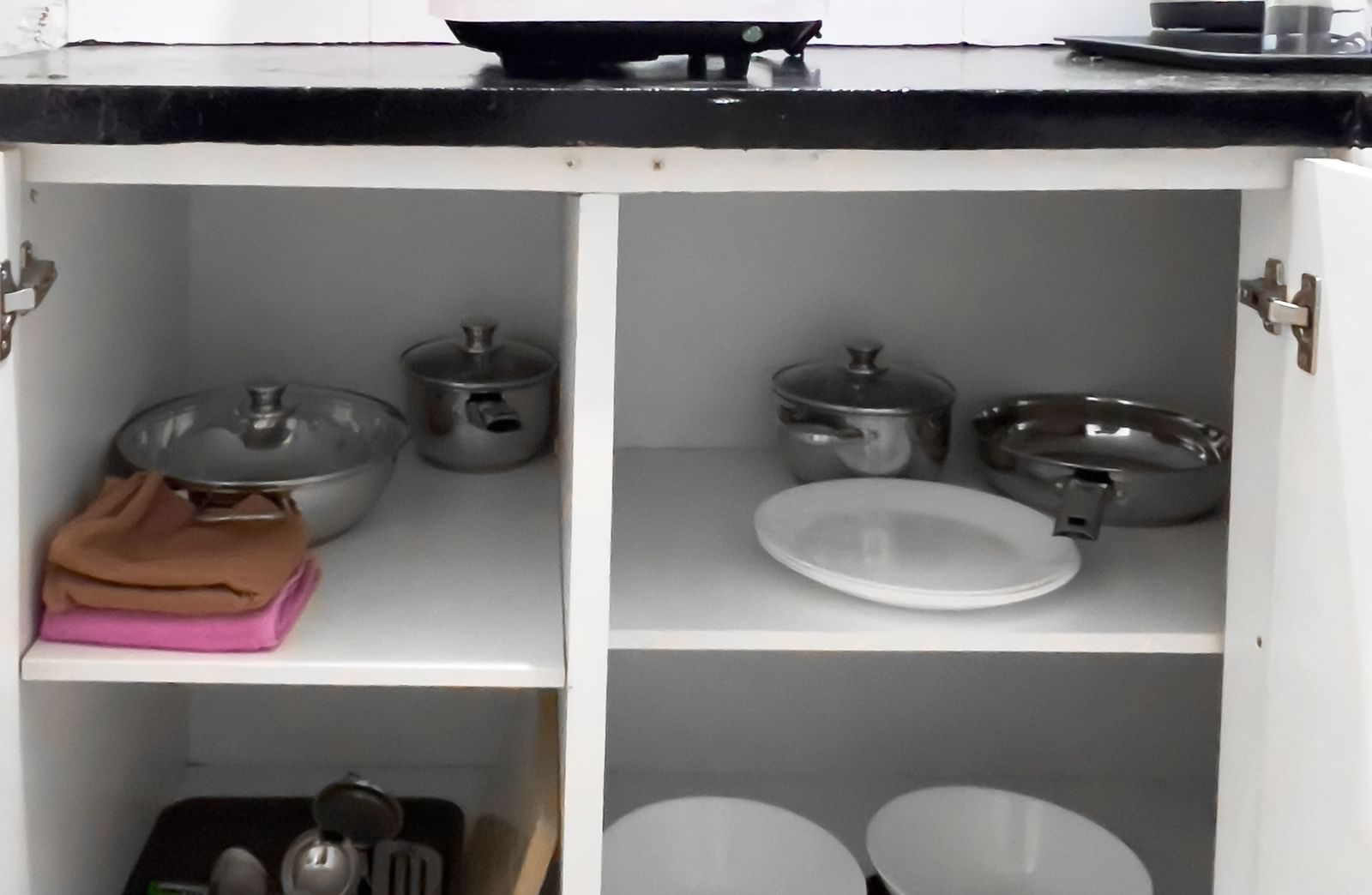 Kitchen cabinet with neatly arranged plates, cups, and cookware at The Pinnacle, Electronic City.
