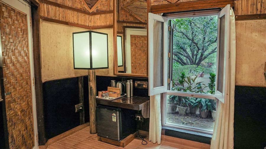 A bedroom with a door leading to the outside, warm lighting, wooden interior - The Den Corbett Resort & Spa, Kumeria.