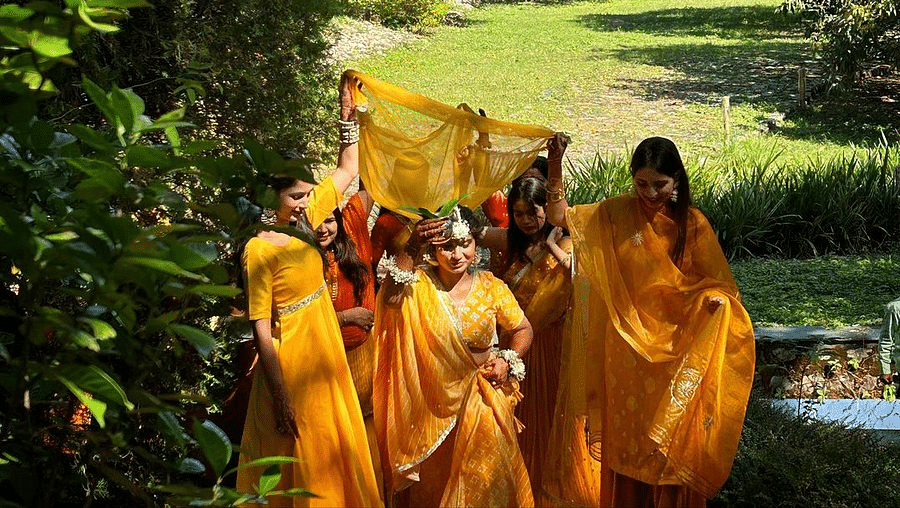 The bride walking alongside her bridesmaids dressed for haldi ceremony surrounded by lush greenery at The Sylvan Retreat, Dehradun.