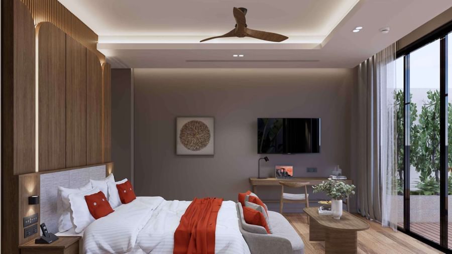 A bedroom featuring a large bed with red pillows, wooden interiors, mounted flat-screen TV, work desk, and sliding glass doors at Ramada Resort by Wyndham Khao Lak.