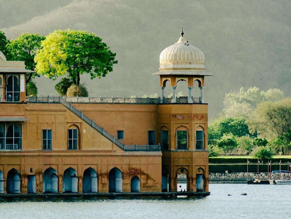 Image of Jal Mahal surrounded by water and mountains in the background.