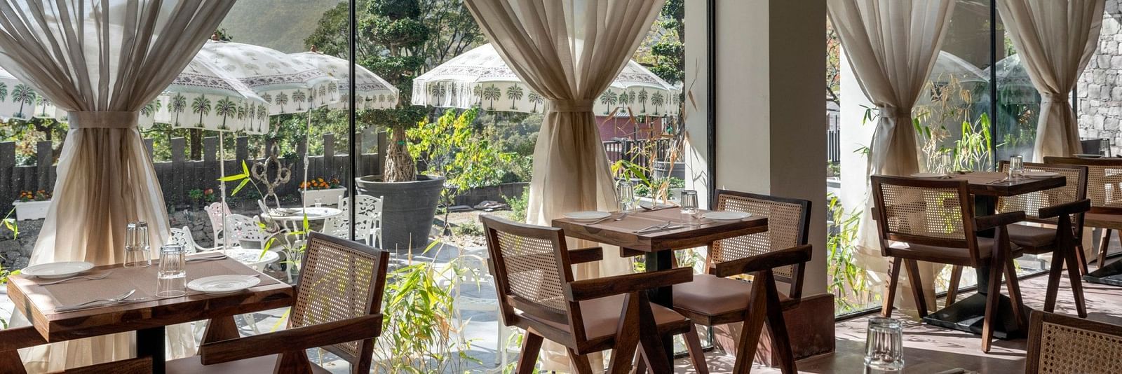 An inside view of a restaurant with chairs placed beside a glass window - The Samai, Bhimtal
