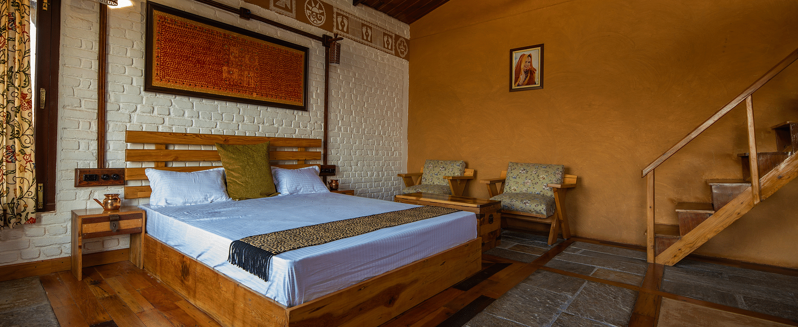 Rustic bedroom with wood bed, patterned textiles, and stairs to right. - Blusalzz Homes The Himalayan Bungalow, Almora