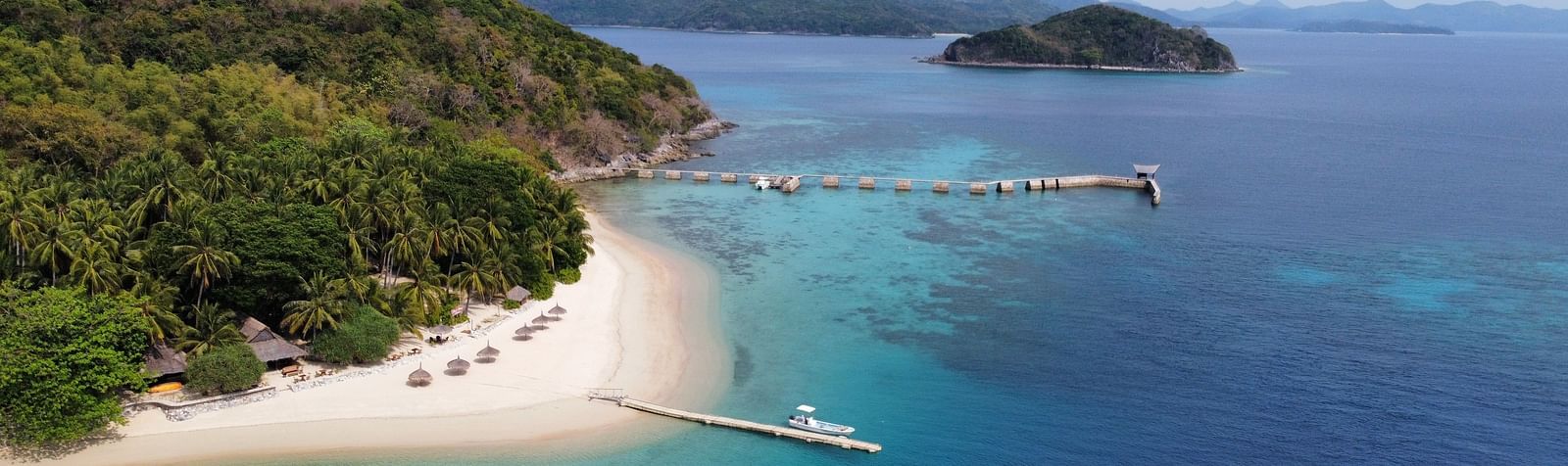 Aerial view of Flower Island Resort surrounded by clear blue water and lush green coastline.