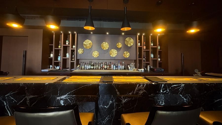 A dimly lit bar with rows of bottles illuminated from behind, highlighting the bar's selection and creating a moody ambiance.