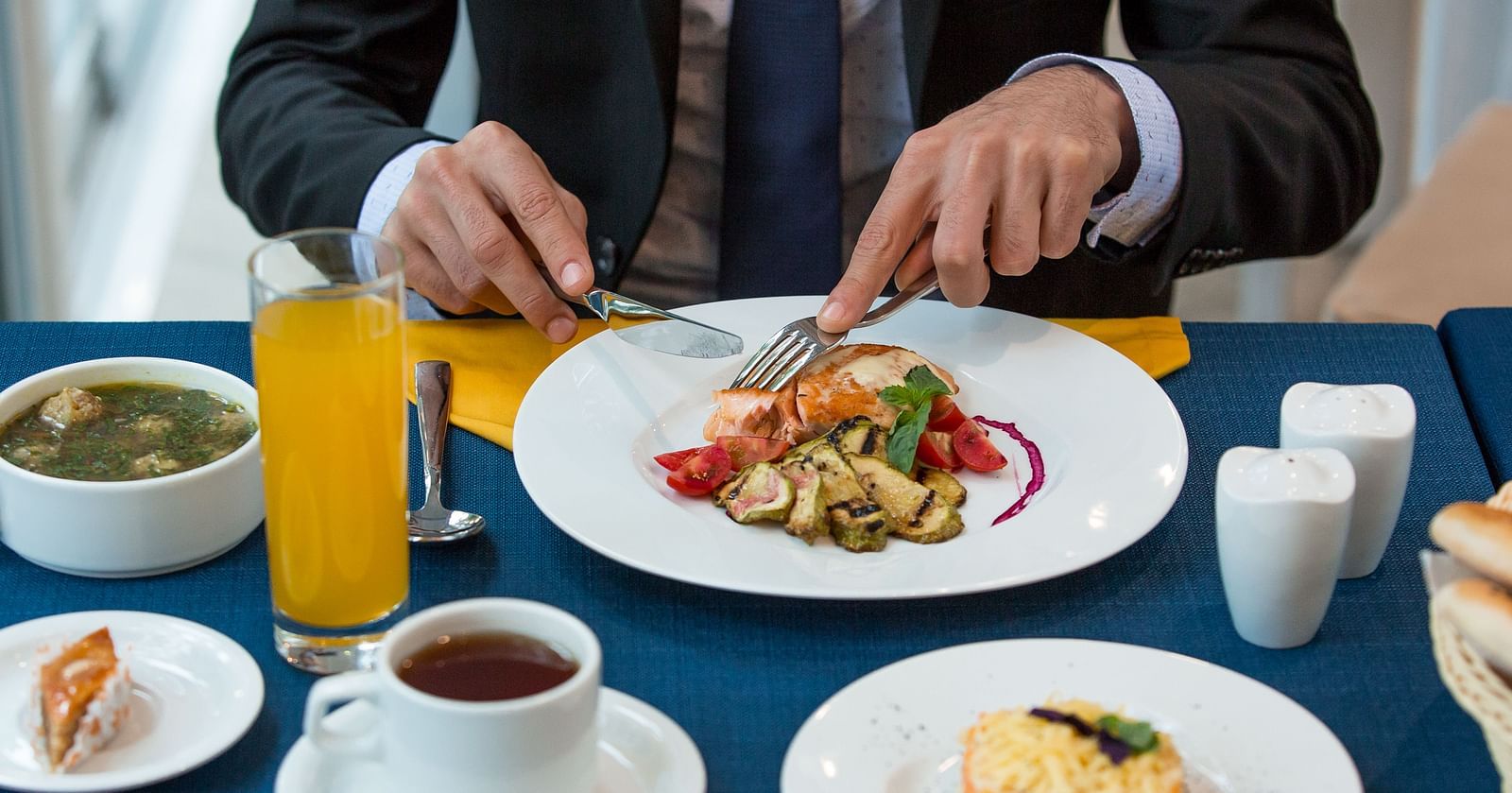 A bsinessman dining with a plate of a gourmet food, orange juice, and tea -  Sitara Luxury Hotel in Hyderabad near Ramoji Film City.