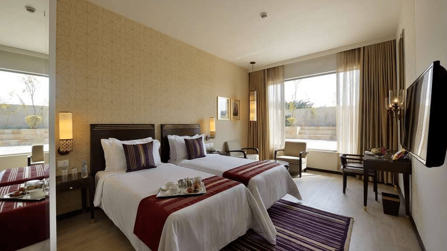 Spacious Premium Twin Room at Marasa Sarovar Premiere, Tirupati featuring twin beds, elegant interiors, a work desk, and large windows with natural light.