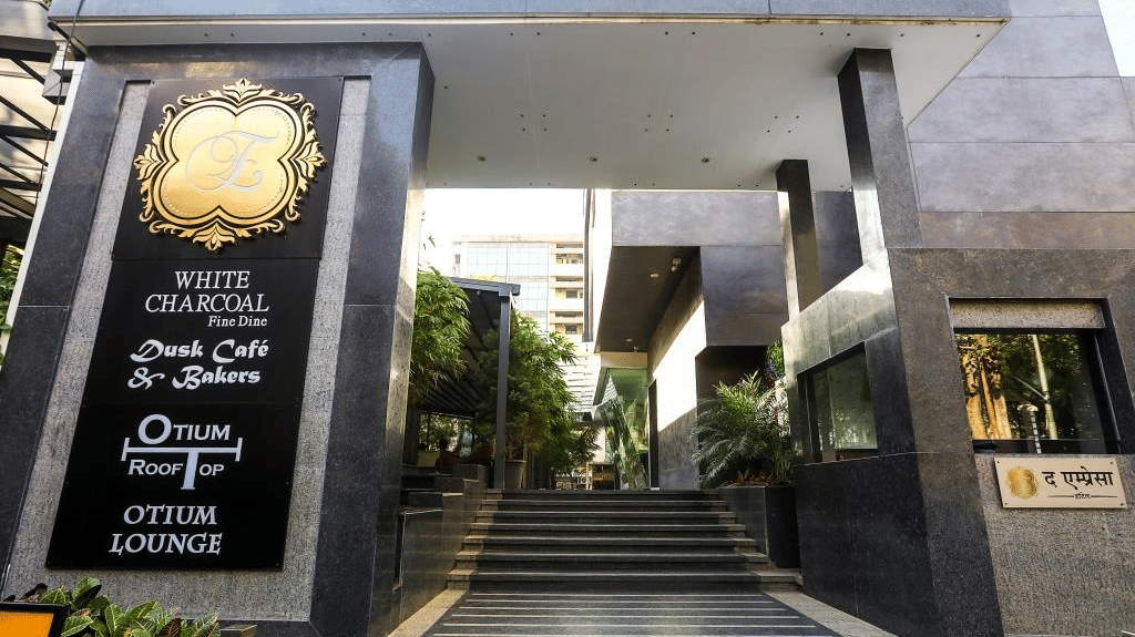Grand building entrance featuring dark granite columns, steps leading up, and black signage plaques on the side.