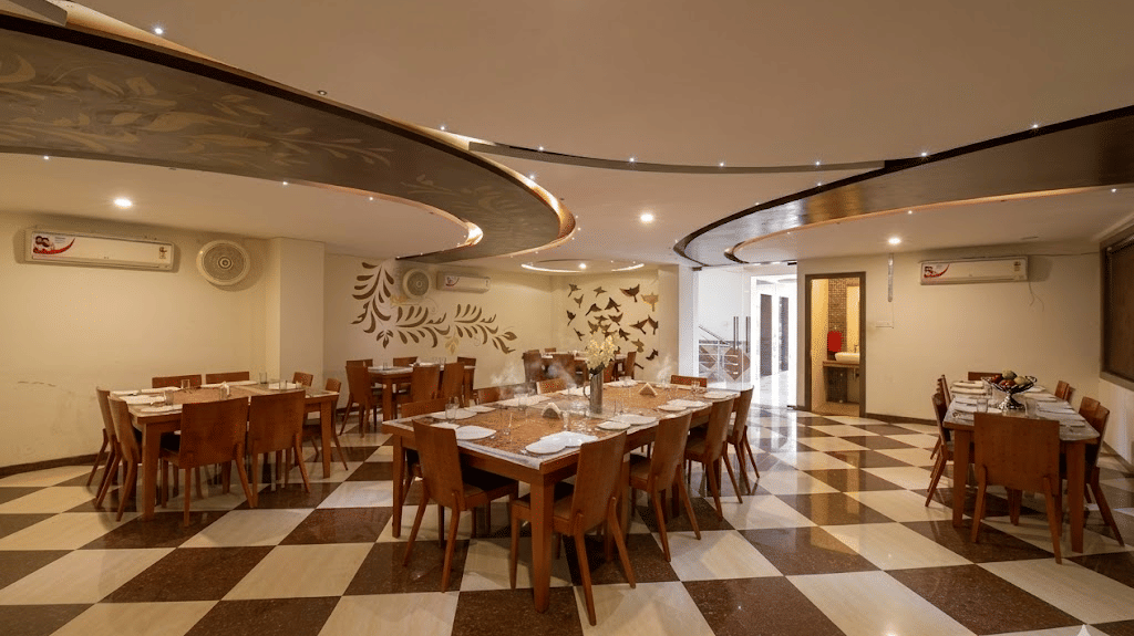 Wide angle view of a dining hall with checkered tile floors, multiple wooden tables, and structured curved ceilings.