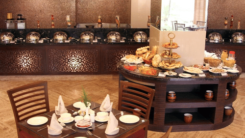 A buffet area at a cafe in Malad West with food laid out and tables and chairs in the foreground.