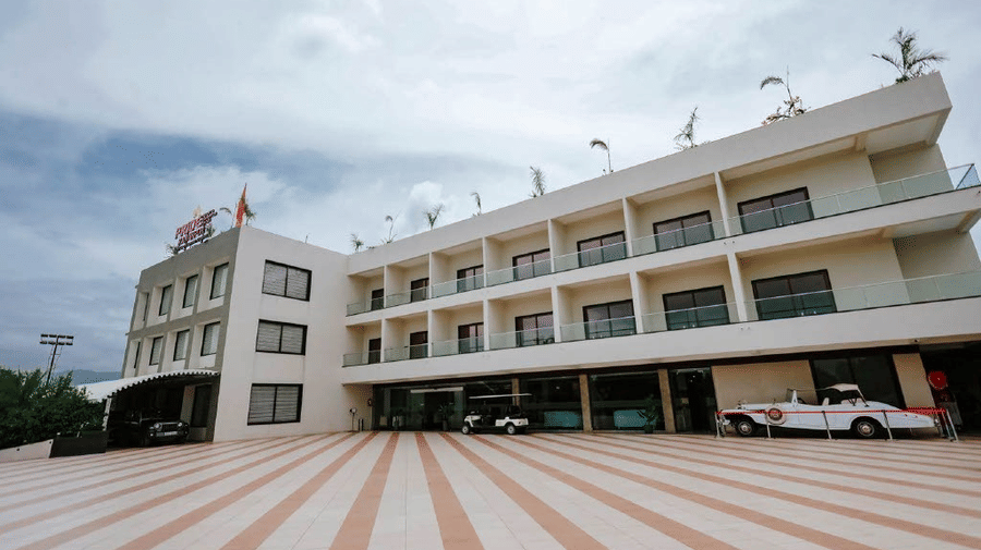A wide shot of the multi-storey Arawali Ananta Elite Jaipur hotel building with a paved driveway and a van parked in front.