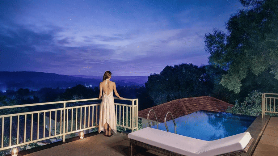 A woman standing by the handrails looking at the cloudy sky from the expansive balcony of the Presidential Suite with Infinity Pool - Golden Tulip Goa Mandrem