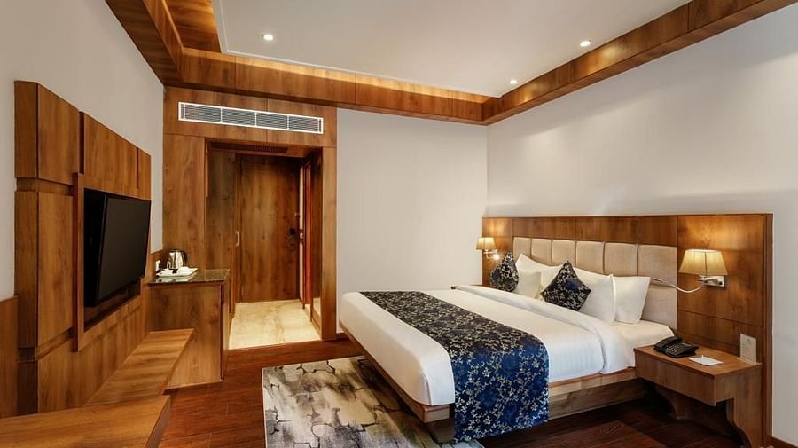 Room with a commodious bed and wooden furnishings at The Orchid Hotel, Manali
