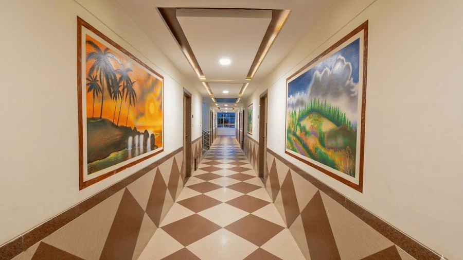 A long hotel corridor with a distinct brown and beige diamond-patterned floor and vibrant wall art panels.