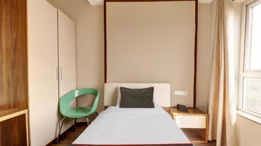 A hotel room with a single bed, a light-coloured headboard, and a green accent chair - VITS Select Kailash Inn, Bagalkot