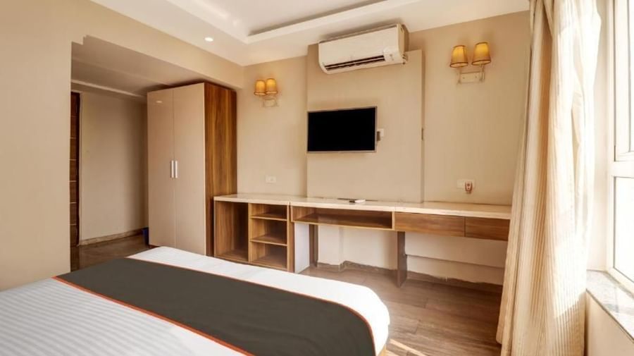 A modern hotel room with twin beds, a wall-mounted television, and a desk - VITS Select Kailash Inn, Bagalkot