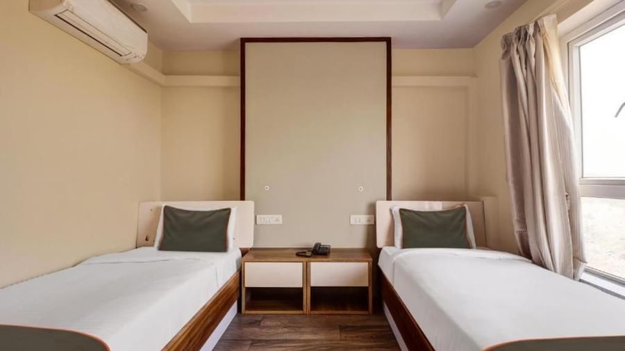 A hotel room with twin beds, light-coloured walls, and tall headboards - VITS Select Kailash Inn, Bagalkot