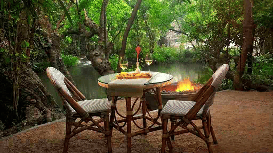 Outdoor dining table under the trees at Amanvana Spa Resort, Coorg