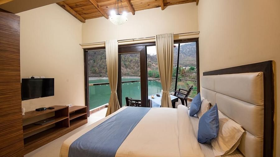 Double bed facing a flat-screen TV and glass doors opening to a balcony 