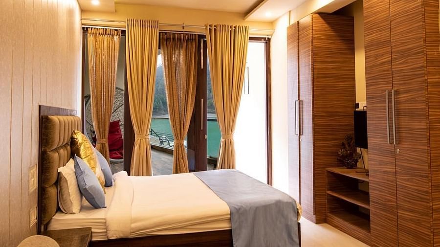 Bedroom with a double bed, wooden wardrobe, TV, and glass doors covered by curtains.