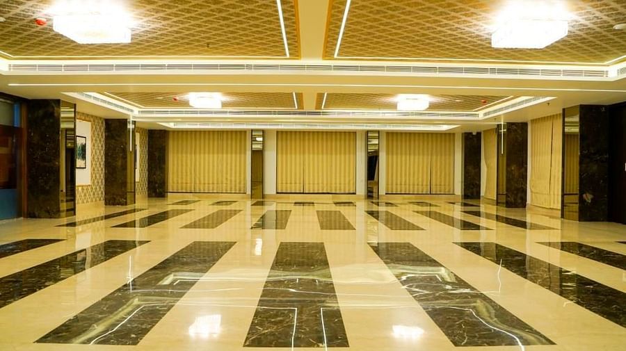 A grand, empty banquet hall at BNGV Grandeur Hotel and Banquets, showcasing a unique striped pattern on its polished floor and illuminated by ceiling lights.