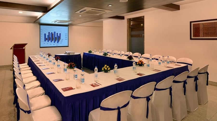 A conference room at the Dwarkadhish Lords Eco Inn set up with a U-shaped table, chairs, and a projection screen.