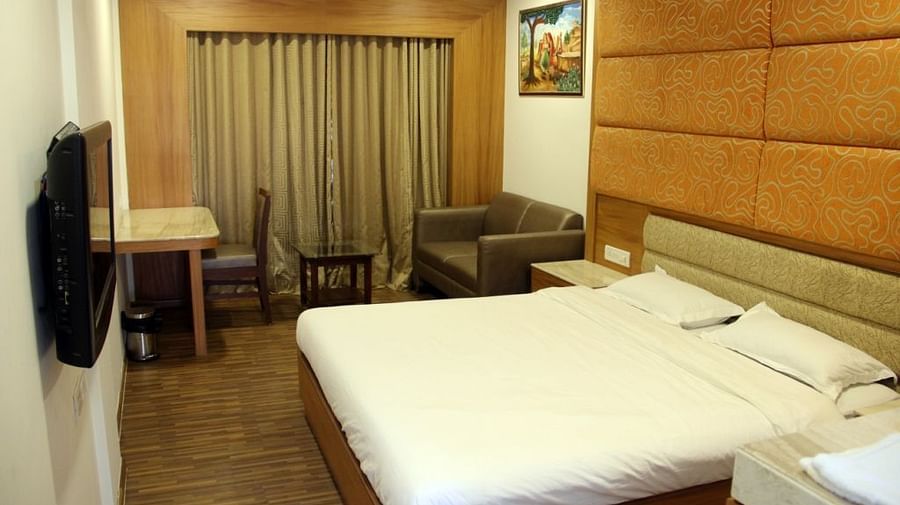 Well-lit hotel room with large bed, work desk, and TV