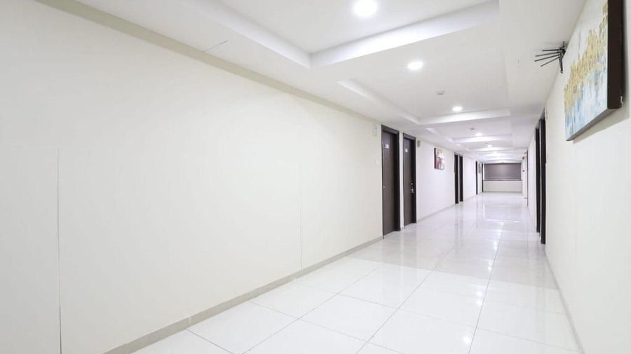 A wide-angle shot of the corridor with white-coloured light coming from the false ceiling at Pravasa Stay, Ahmedabad (Alba Premier).