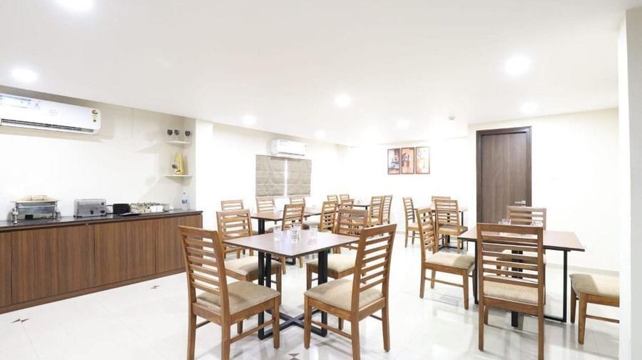Corner view of the restaurant in a brightly-lit indoor space at Pravasa Stay, Ahmedabad (Alba Premier).