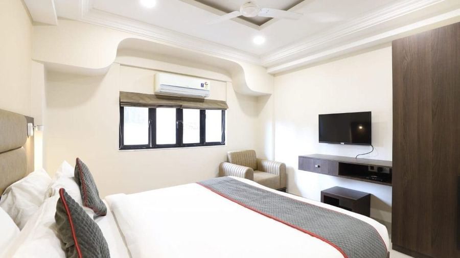 A wide-angle shot of the Premium Room at Pravasa Stay, Ahmedabad (Alba Premier), featuring a double bed along with a wall-mounted television.