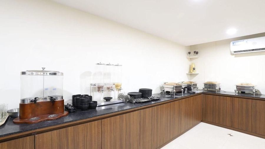 A wide-angle shot of the buffet counter at Aranaya Restaurant at Pravasa Stay, Ahmedabad (Alba Premier), with wooden panels covering the bottom of the counter. 