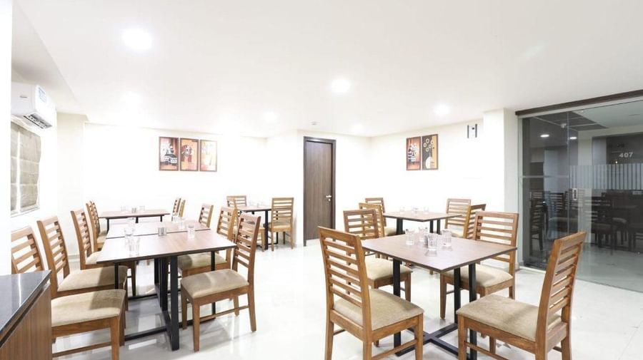The interiors of Aranaya Restaurant at Pravasa Stay, Ahmedabad (Alba Premier), featuring well-arranged dining tables.