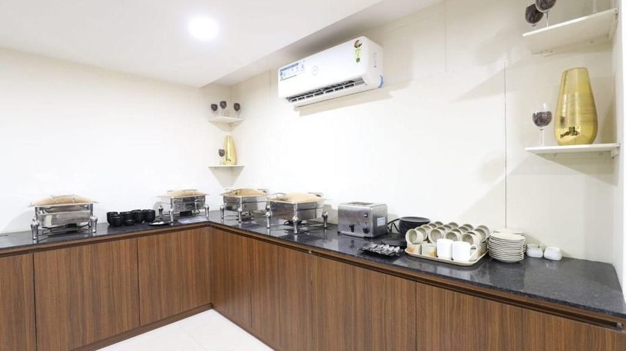 The buffet counter at Aranaya Restaurant at Pravasa Stay, Ahmedabad (Alba Premier), with a wall-mounted split AC above it.