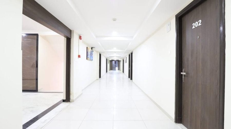 A brightly-lit corridor at Pravasa Stay, Ahmedabad (Alba Premier), with several doors lined up.