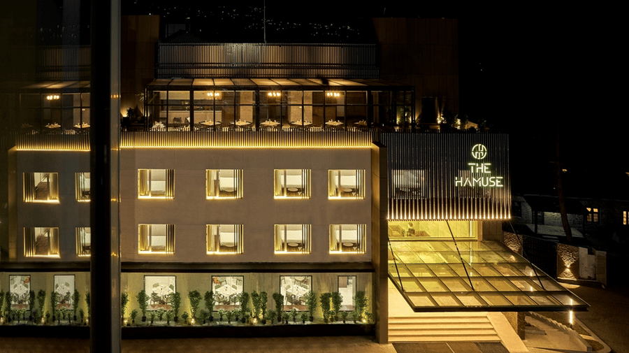 The Hamuse Hotel, Kodaikanal facade with of windows and the rooftop dining area.