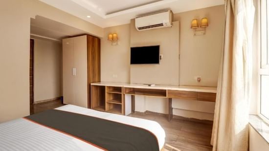 A modern hotel room with twin beds, a wall-mounted television, and a desk - VITS Select Kailash Inn, Bagalkot