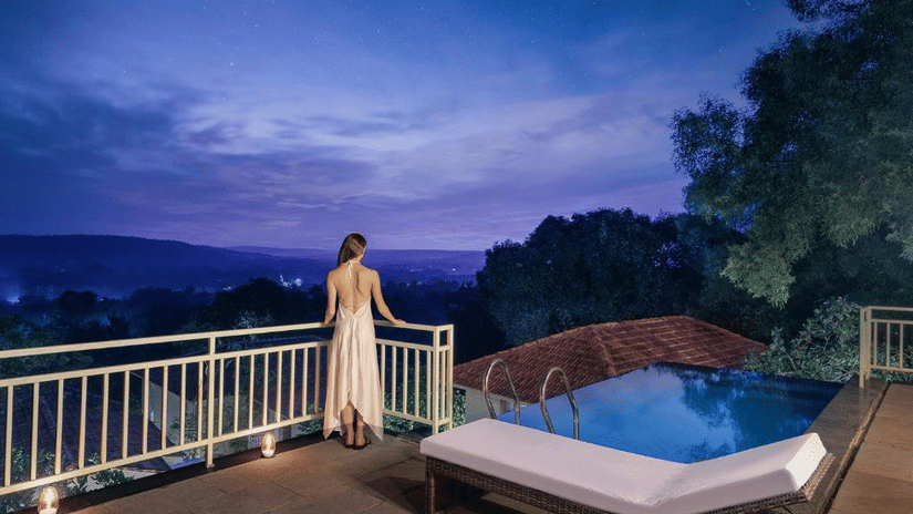 A woman standing by the handrails looking at the cloudy sky from the expansive balcony of the Presidential Suite with Infinity Pool - Golden Tulip Goa Mandrem