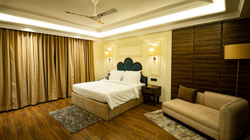 Side view of luxury villa room with a cozy, spacious bed and a sofa in the corner at Wedlock Greens Hotel & Resort, Dhanbad
