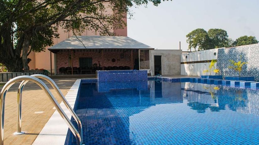Overview of the swimming pool with a building in the background - Hotel Wedlock Greens, Dhanbad