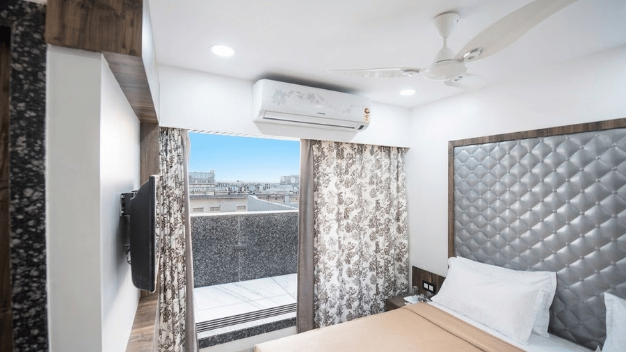 Royal suite of Adamo Sanmukh with modern interiors and air-coditioner and a balcony in view.