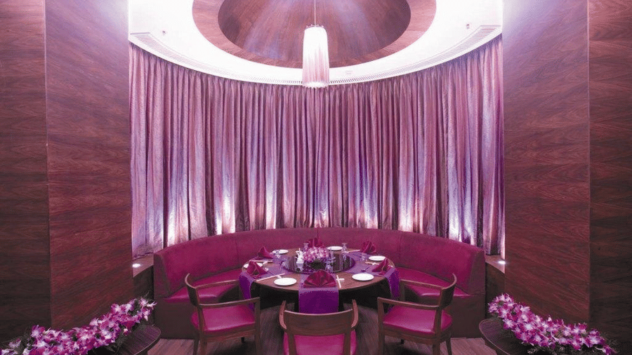 A table and chairs, under a circular light with curtains in the background.