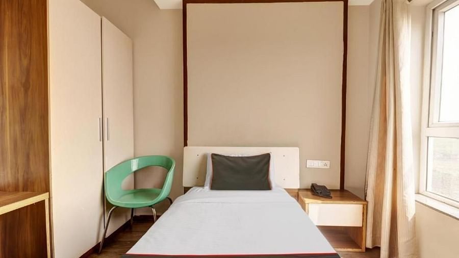 A hotel room with a single bed, a light-coloured headboard, and a green accent chair - VITS Select Kailash Inn, Bagalkot