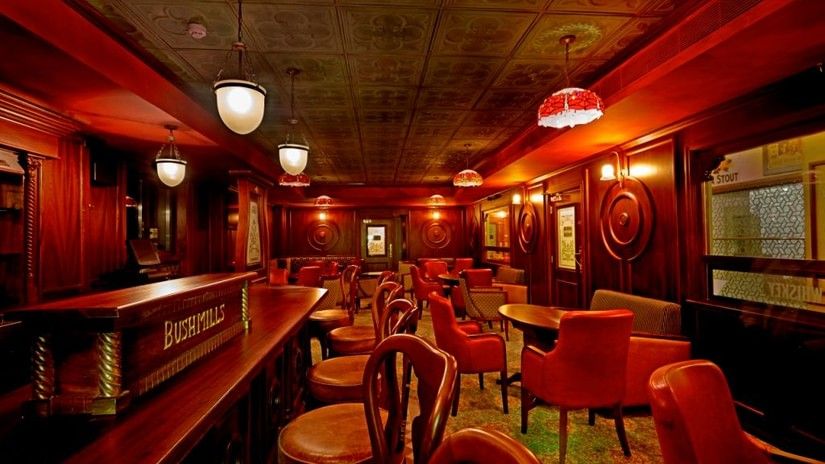 Moon and Sixpence at Hablis Hotel featuring vintage-style interior with warm lighting, wooden furniture and red upholstered chairs