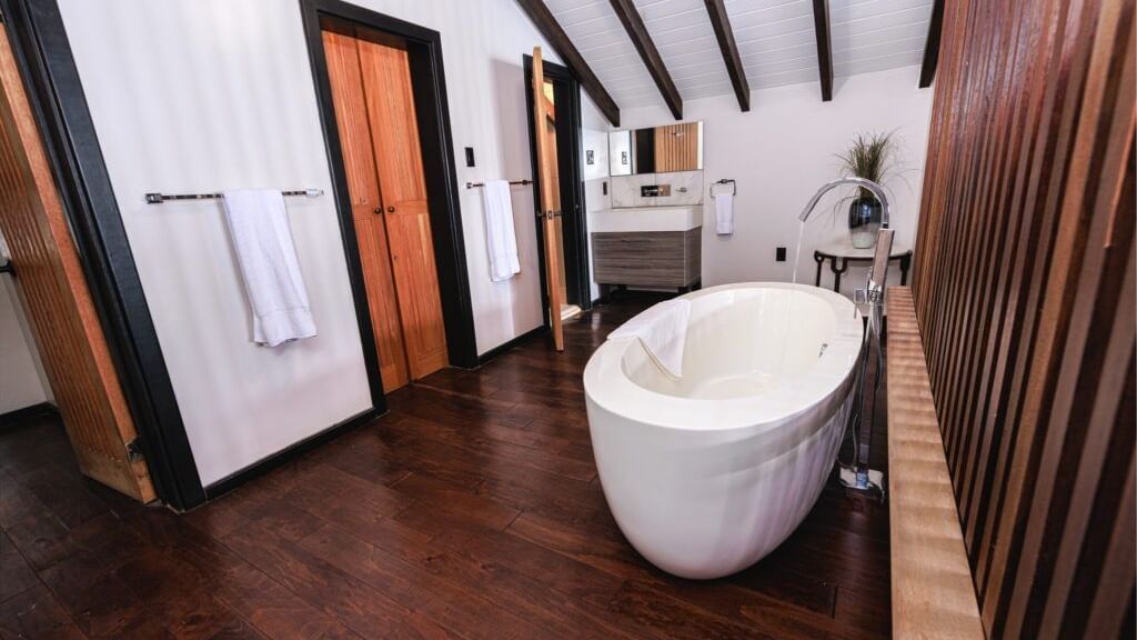 A luxurious bathroom featuring a modern freestanding bathtub and dark wood accents.
