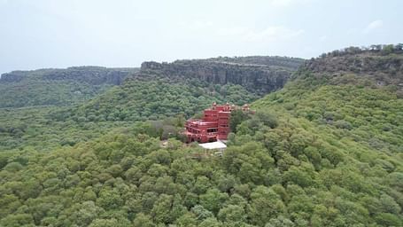 A serene image of Hotel Castle Jhoomar Baori nestled in between lush greeen trees