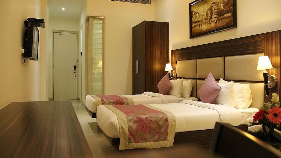 Image of well lit Deluxe Room featuring twin beds and a TV in front of them