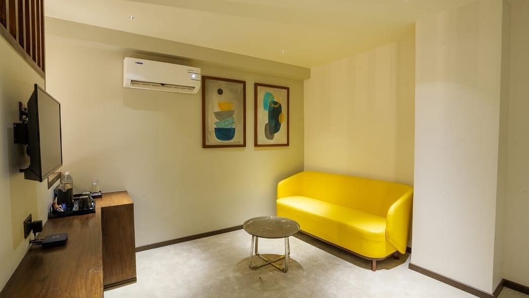 A living room in a suite with a television, a ac and a sofa -  Visthara - Urban Boutique Hotel