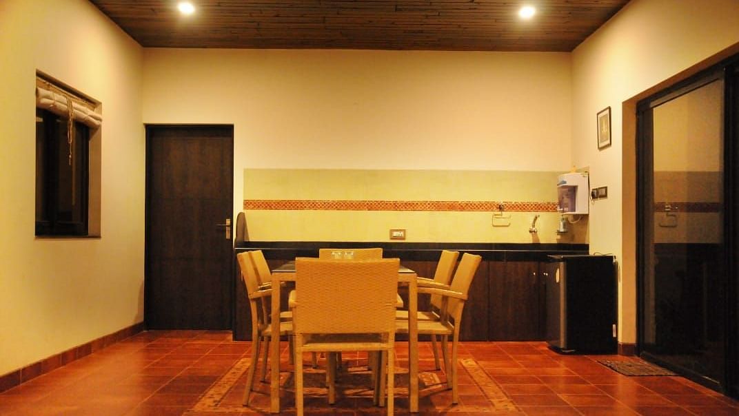 A dining room with a wooden table and chairs, dark wood cabinets, a window, and a door leading outside.